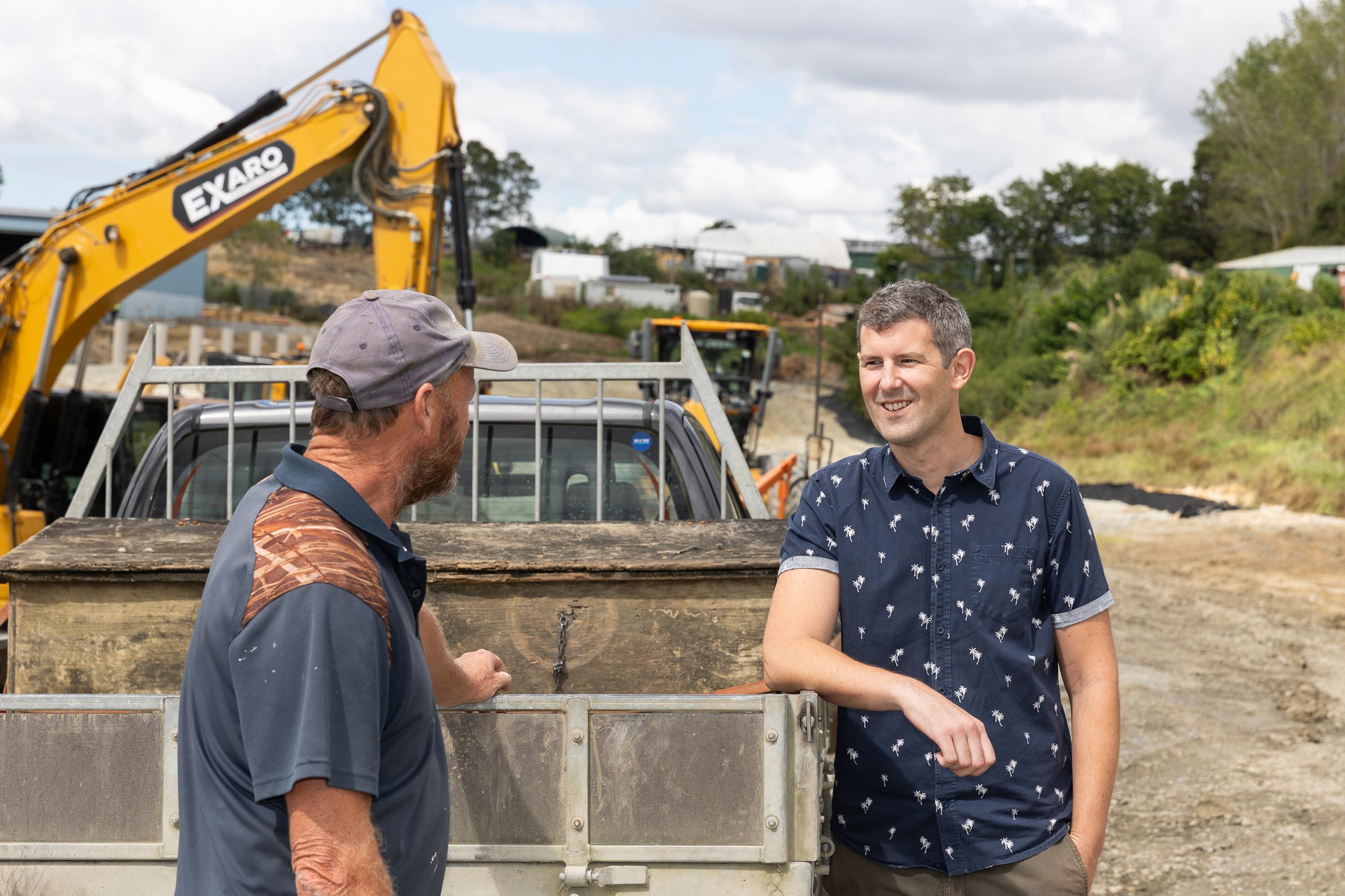 Lawyer talking to developer on site with digger in the background